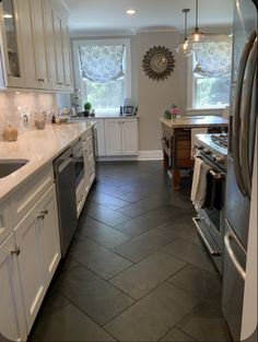 a large kitchen with white cabinets and stainless steel appliances, along with tile flooring