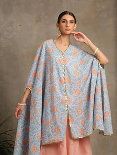 Set of 2 consists of cape and sharara pants. Bouquet of floral peaches hand-printed on a soothing blue cotton base. A quintessential summer cape/kaftan set perfect for the upcoming festivities. Comes with dainty gota highlights and handmade button detailing. Combined with sharara pants in peach with handwork zari and gota detailing Colour - Blue Fabric - Cotton Occasion - Festive Wear Fit - Relaxed and Flowy Pattern - Printed Care - Dry Clean only Estimated Delivery 15-20 days Heer- These are fi Kaftan Set, Cape Set, Sharara Pants, Festive Wear, Festival Wear, Blue Fabric, Fabric Cotton, Cape, Print Patterns