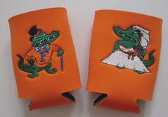 two orange can coolers with embroidered images of alligators on them, one is wearing a top hat and the other has an umbrella