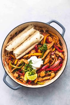 chicken fajita in a skillet with tortillas and sour cream