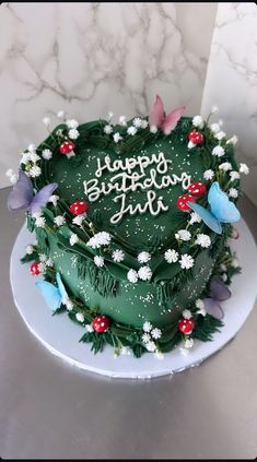 a green birthday cake with white flowers and butterflies