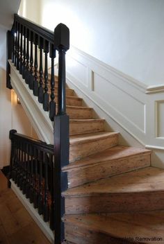 a wooden stair case next to a white wall