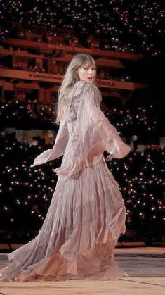 a woman in a long dress walking down a runway