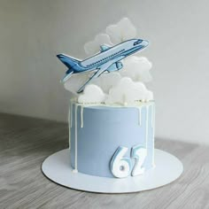 a blue and white birthday cake with an airplane on top that is decorated in icing