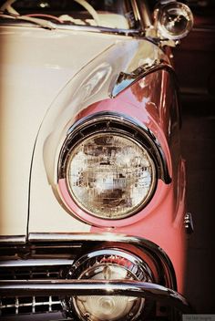 the front end of a red car with its lights on and headlight turned off