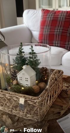 a basket filled with christmas decorations on top of a table next to a white couch