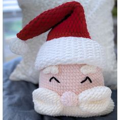 a crocheted santa clause doll sitting next to a pillow