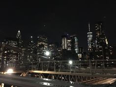 the city skyline is lit up at night, with lights shining on buildings and bridge railings