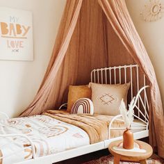 a bed with a canopy over it and pillows on the bottom floor in a bedroom