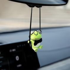 a green frog hanging from the dashboard of a car