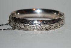 This is a vintage sterling silver bangle with safety chain and an engraved foliate design on half the bangle. In good condition with no repairs or restoration and may show signs of wear consistent with normal use; we have not cleaned or polished this so there may be some tarnish. All sales are final, please be sure when you buy; please view all pics for size and detail, they constitute part of the description.  SKU# u26.1805 Please view all pics for size and detail. Buying and selling antiques s Hallmarked Vintage White Gold Bangle, Vintage Hallmarked White Gold Bangle, Vintage White Gold Hallmarked Bangle, Vintage Engraved White Gold Bracelets, Victorian Sterling Silver Engraved Wedding Bracelet, Vintage Sterling Silver Bracelet With Intricate Design For Anniversary, Vintage White Gold Round Bangle, Vintage Hallmarked Sterling Silver Bracelet, Antique Sterling Silver Bangle Bracelet For Wedding