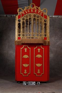 an old fashioned red and gold ticket booth