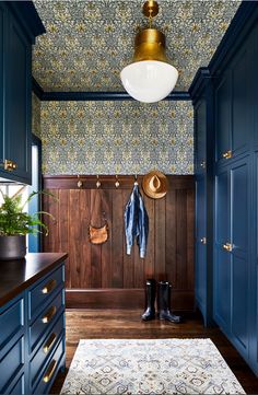 a blue and gold entryway with wood paneling, wallpaper and coat rack