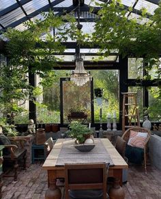 an outdoor dining area with lots of plants in the center and large windows above it