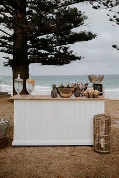 an outdoor bar on the beach next to some trees and water in the ocean behind it