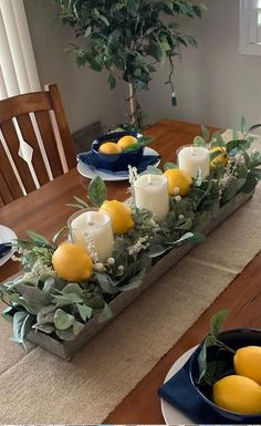 the table is set with candles, lemons and greenery in blue dishes on it