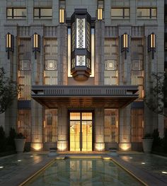 the front entrance to a building lit up at night with water reflecting in the pool