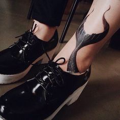 a person with tattoos on their legs wearing black shoes