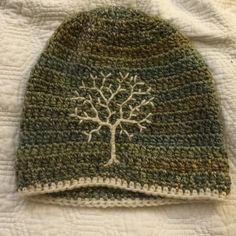 a crocheted hat with a tree on it sitting on top of a bed