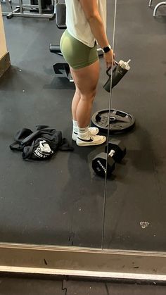 a woman standing on top of a gym floor next to a barbell exercise machine