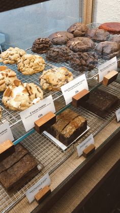 a display case filled with lots of different types of cookies and brownies on top of metal racks