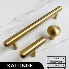 two brass handles and knobs on a white marble countertop with text reading kallinge hardware shop