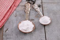 two spoons filled with sugar sitting on top of a wooden table