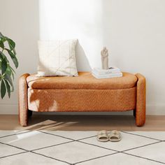 a living room scene with focus on the footstool and floor rug, which has a plant next to it