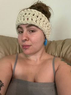 a woman sitting on a couch wearing a crochet headband