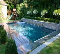 a small swimming pool in the middle of a yard with flowers and trees around it