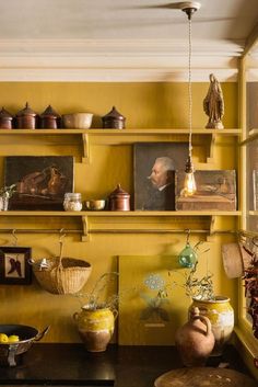 a kitchen with yellow walls and shelves filled with pots, pans and other items