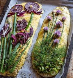 two fish fillets with herbs and onions on a baking sheet lined with parchment paper