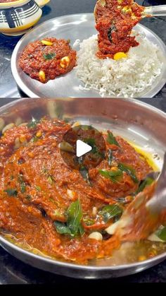 two metal pans filled with food on top of a table next to rice and sauce