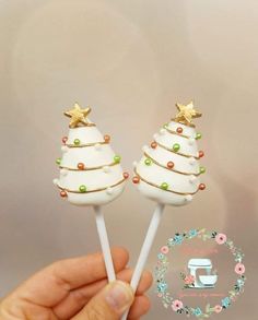 there are two white christmas trees on top of lollipops with gold stars