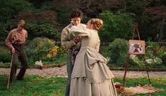 two people dressed in period clothing standing next to an easel and painting on the ground