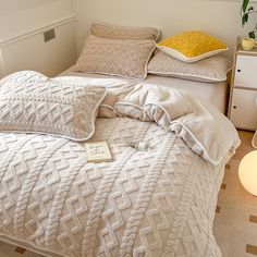 a white bed with two pillows on top of it and a yellow pillow next to it