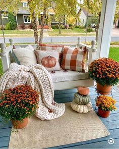 a porch swing with pumpkins and flowers on it