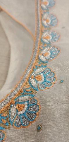 an embroidered fabric with blue and orange flowers on it's side, in the middle of