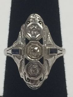 "Vintage 1940's 14K White Gold .50CTW Diamond and Sapphire Ring This beautiful, well made ring will become a family heirloom! 2 round .15ct diamonds set in a row with 2 - .3ct sapphires on side of band. Ring face measures approximately 1\" x 1/2\" Size 6.25 3.1 grams total weight. In excellent vintage condition!" Vintage 14k Stamped Sapphire Ring For Formal Occasions, Antique Three Stone Round Diamond Ring, Antique Platinum Three Stone Diamond Ring, Antique Three-stone Diamond White Rings, Antique Three Stone Diamond White Rings, Antique Oval Three Stone Diamond Ring, Antique Platinum Three-stone Jewelry, Vintage 14k Gold Three-stone Rings, Vintage 14k Gold Three Stone Rings