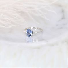 a ring with a blue stone on it sitting on top of a white marble surface