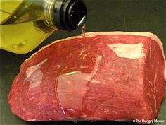 a piece of raw meat is being poured with olive oil onto the top of it