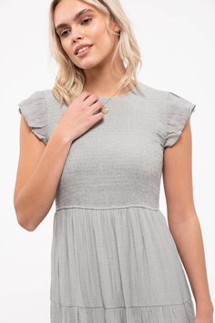 This solid midi-length dress features a smocked body, tiered skirt, and round neckline with a back button and ruffle cap sleeves. Both casual and elegant, this will be a summer staple. Spring Midi Dress With Smocked Bodice And Ruffle Sleeves, Elegant Smocked Short Sleeve Dress With Ruffles, Flutter Sleeve Midi Dress With Smocked Back For Brunch, Chic Smocked Dress With Flutter Sleeves For Spring, Chic Smocked Dress With Flutter Sleeve And Ruffle Hem, Short Sleeve Midi Dress With Smocked Bodice, Elegant Smocked Dress With Ruffle Sleeves For Spring, Elegant Smocked Dress With Ruffle Hem And Sleeves, Elegant Smocked Dress With Flutter Sleeves For Summer