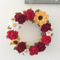 a crocheted wreath with flowers hanging on the wall