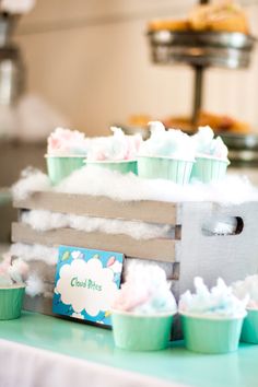 some cupcakes are sitting on a table with clouds in the air around them