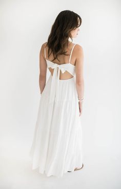 A white maxi dress is a summer must have! This stunning dress has a flowing silhouette and a classic white hue, exuding timeless charm. The open back with tie detailing adds a touch of allure and sophistication. Perfect for beach weddings, garden parties, or pretty much anything else you have going on this summer! This is a dress you will reach for over and over again. Size Chart Features: v neckline open scoop back with tie detail maxi length fully lined fabric content: 100% rayon model is wear White Long Sundress, White Sundress Long, Beachy Maxi Dress, White Beach Dress, Beach White Dress, Long Sundress, Maxi Dress White, White Maxi Dress, Long White Dress