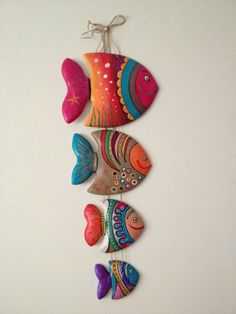 three colorful fish hanging on a white wall