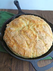 a cast iron skillet filled with bread on top of a wooden table next to a green towel