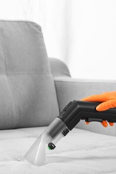 a person with an orange glove is cleaning a couch