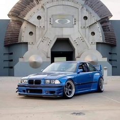 a blue bmw is parked in front of a building with a large circular window and door