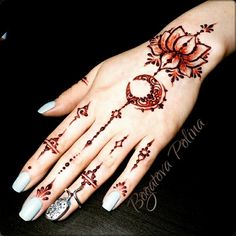 a woman's hand with henna tattoos and flowers on her fingers, showing the design